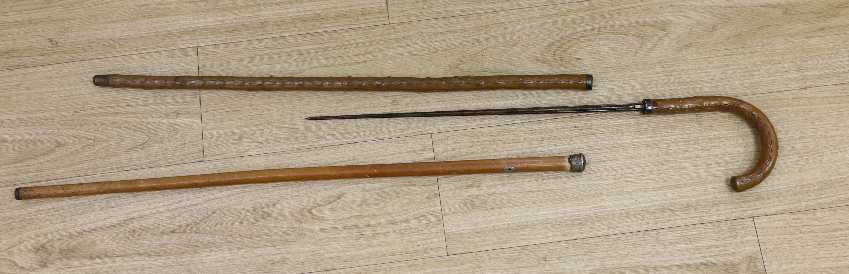 An early 20th century sword stick and a metal topped cane, sword stick 91cm long